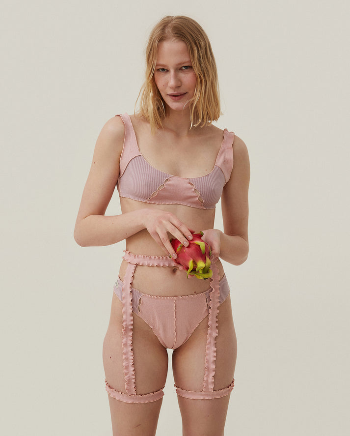 Pink ribbed thong with scalloped edges and front panel seam, worn with garters