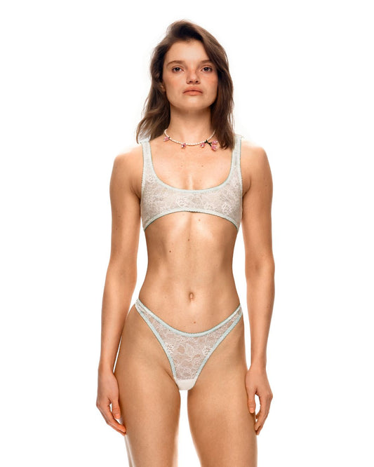 Lace bralette top on model with scoop neckline and contrast elastic trim, light color