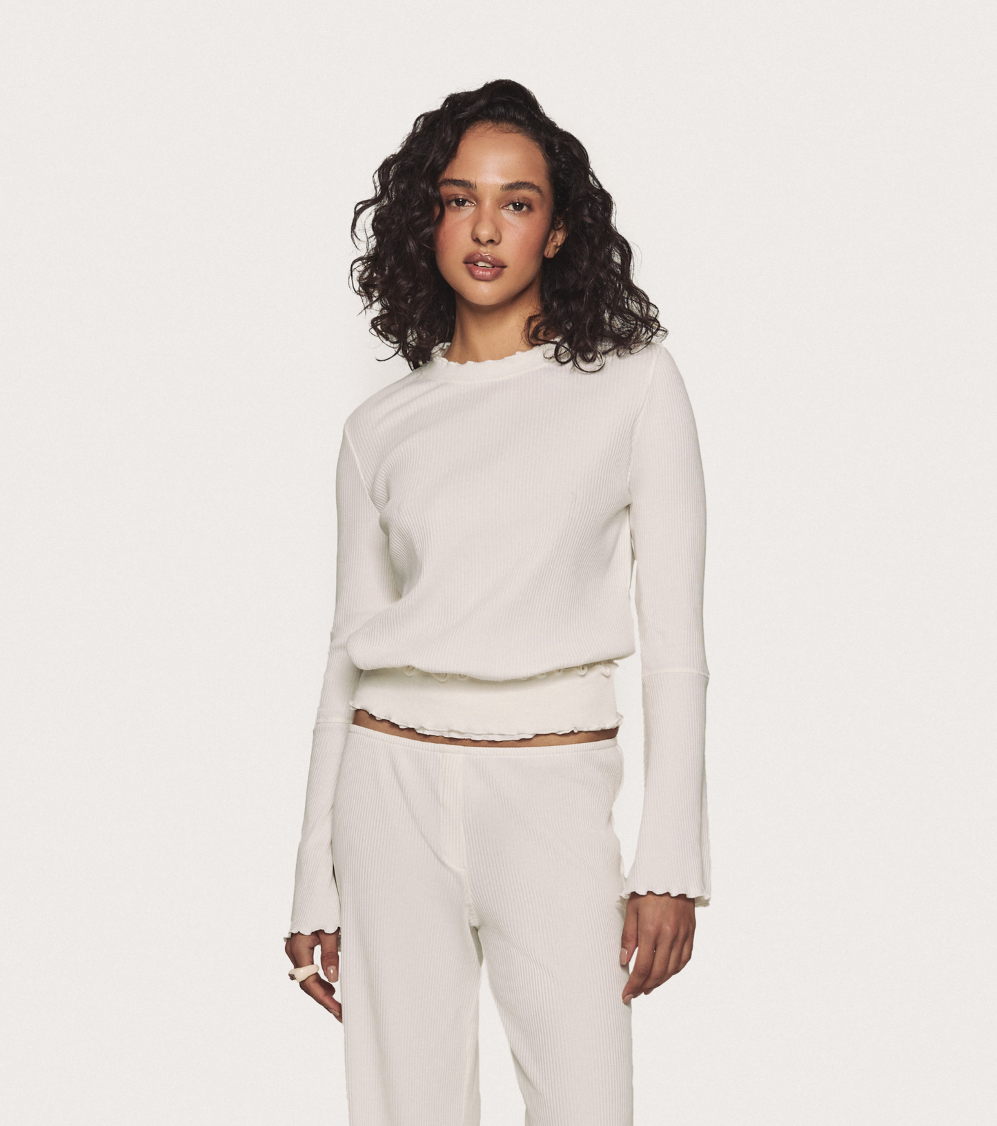 Wavy long-sleeve top in white, ribbed knit with ruffled hem and bell sleeves