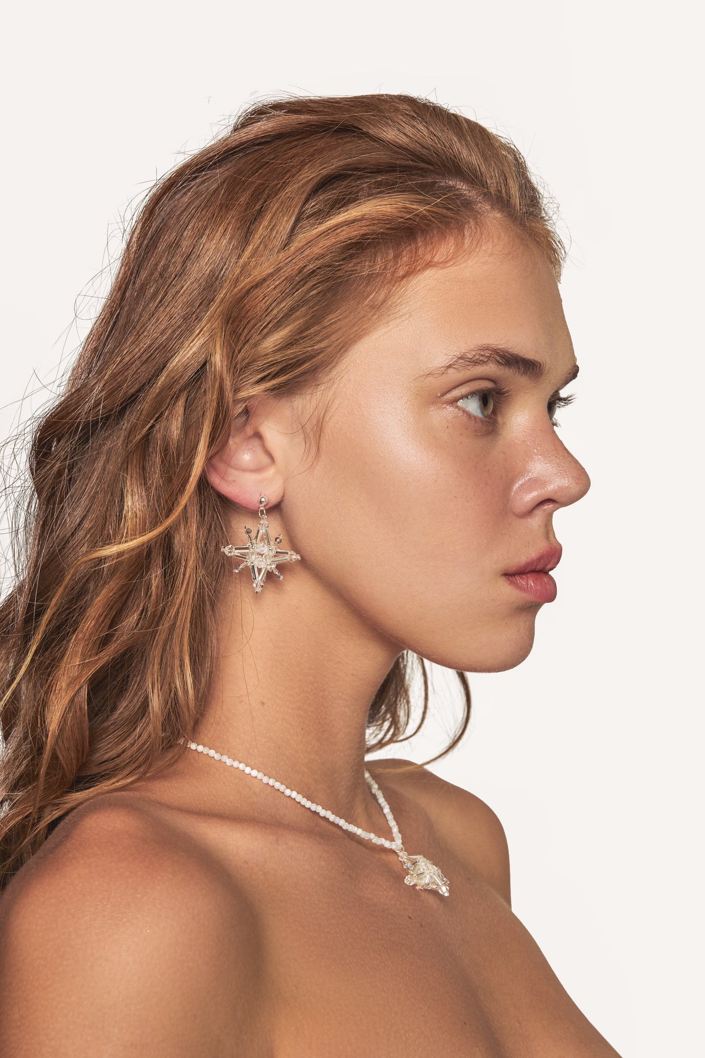 Crystal starburst drop earrings on model, silver-tone hooks with clear stones