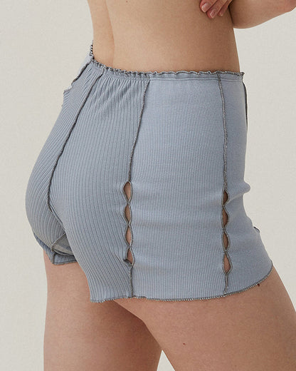 Light blue ribbed knit shorts with elastic waist and side cutouts, scalloped hem, loop stitching.