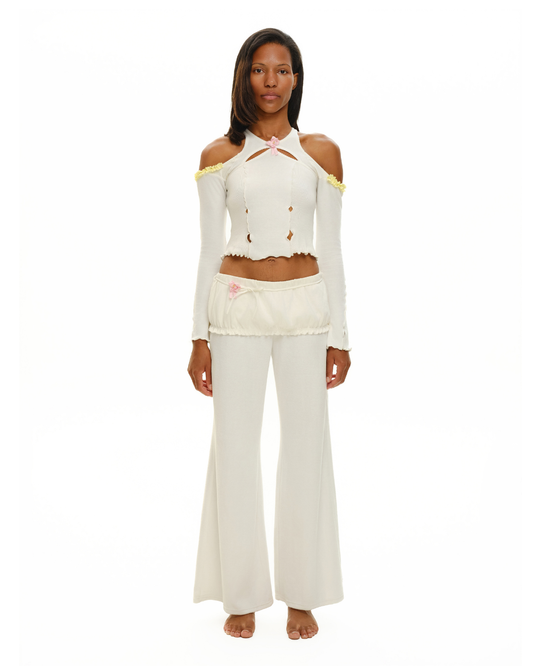 White off-shoulder long-sleeve crop top with pink rosette neck detail and wide-leg pants