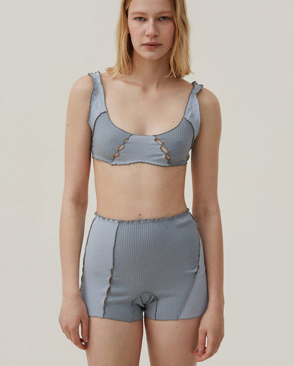 Light blue ribbed knit shorts with elastic waistband and scalloped hem, decorative loop details.
