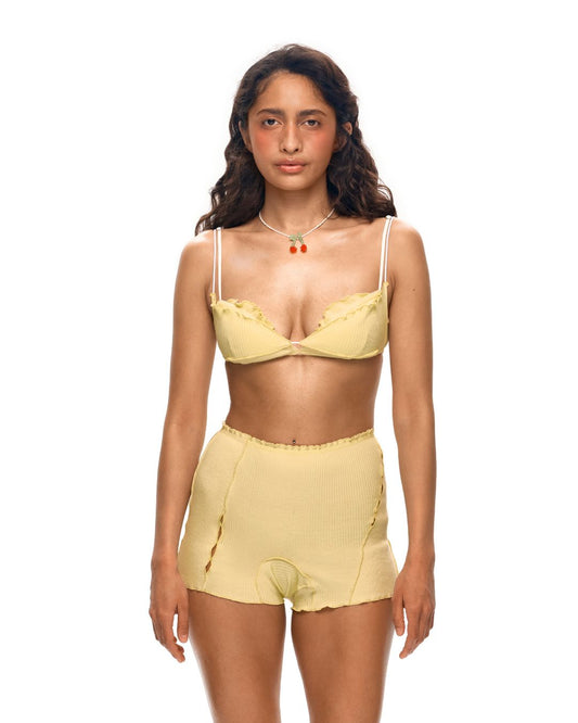 Pale yellow layered underwire bra with thin straps and scalloped lace trim, worn