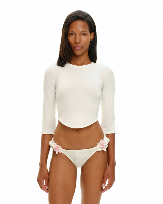 White long-sleeve crop top with scalloped trim over bikini briefs with pink floral side ties
