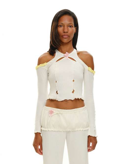 White off-shoulder long-sleeve crop top with pink rosette at neckline and ruffled trim