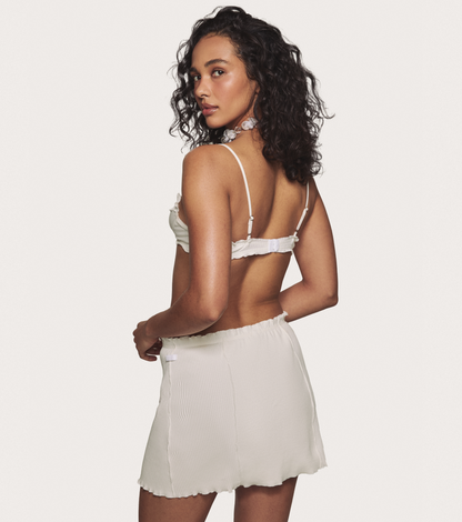White mini skirt with elastic waistband and textured ribbed fabric, ruffled edge
