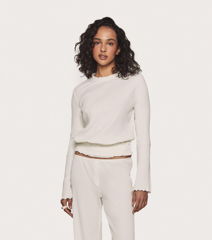 Wavy long-sleeve top in white, ribbed knit with ruffled hem and bell sleeves