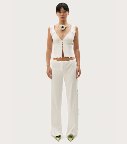 White short tank top with ruffled trim, deep V front, and sleeveless silhouette.