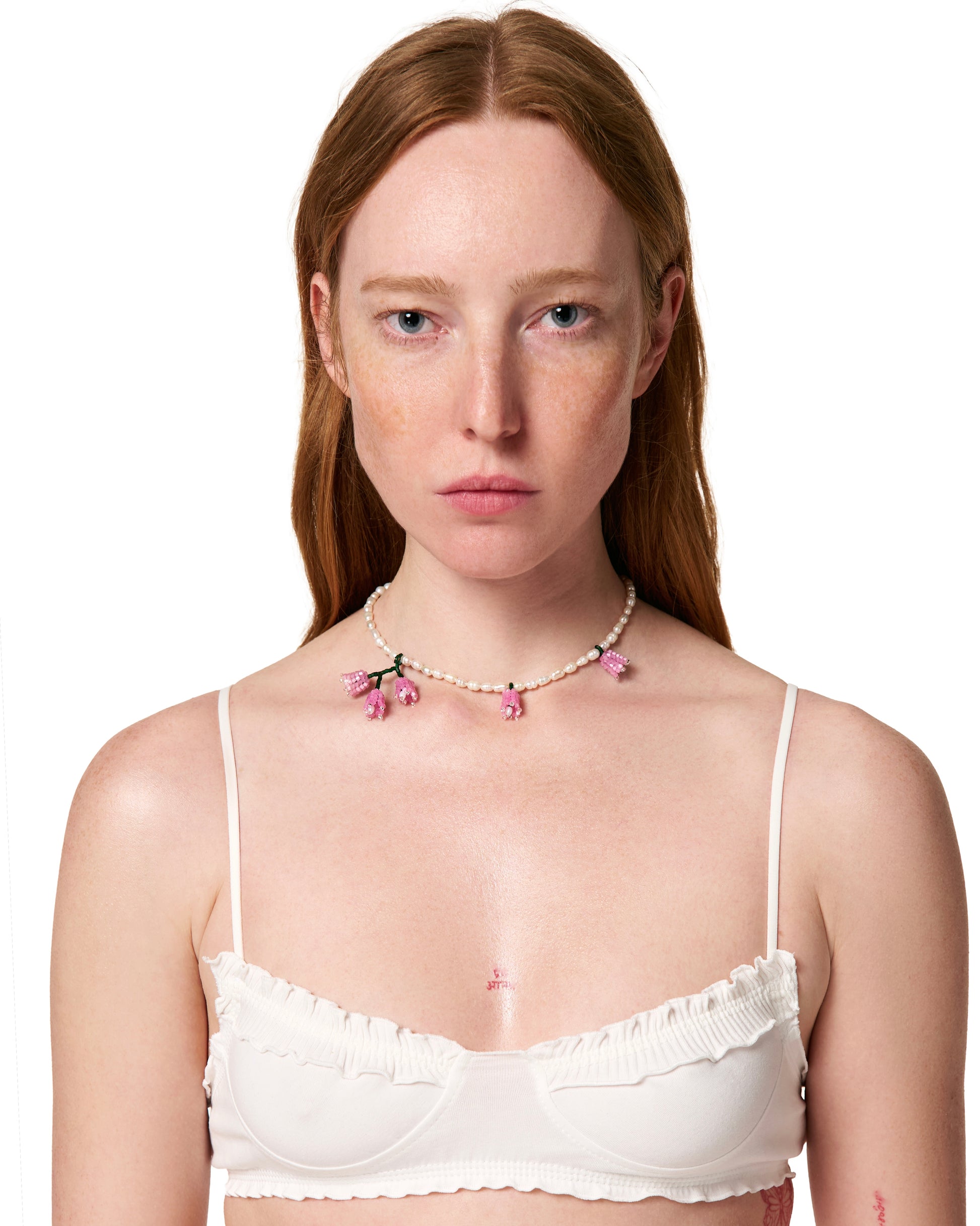 Pearl bead necklace with small pink flower charms worn at the collar