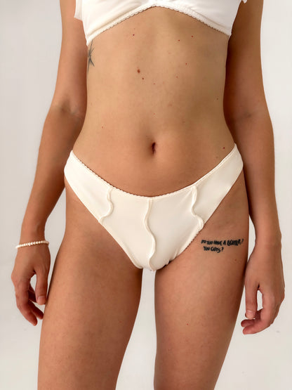 White bikini bottoms with ruffled edges and wavy side seam detail