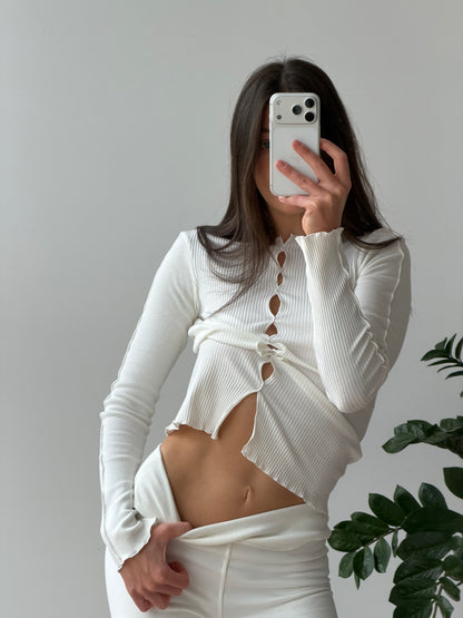 White long-sleeve ribbed top with draped center cutout and asymmetrical hem