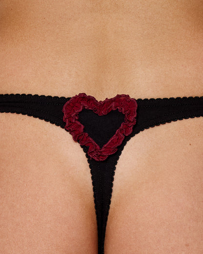 Black thong close-up with red heart applique and scalloped trim