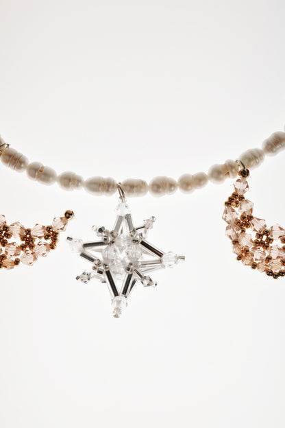 Pearl-bead necklace detail: clear star pendant with crystal arms and warm-gold clusters