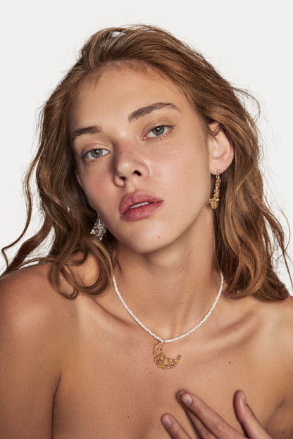 Moon necklace on model: white bead chain with gold crescent moon charm