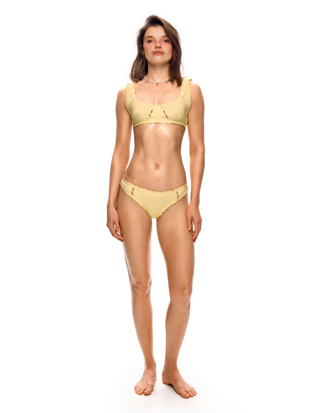 Yellow tanga underwear on model, minimal coverage with scalloped trim