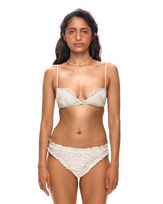 White lace bra with light blue trim, underwire cups, and thin spaghetti straps