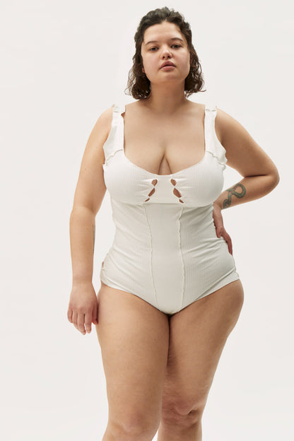White ribbed bodysuit with thin straps, chest cutout, and full-coverage leg
