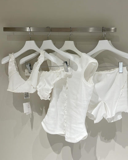 White draped sleeveless T-shirts on hangers, showing center-front cutout detail